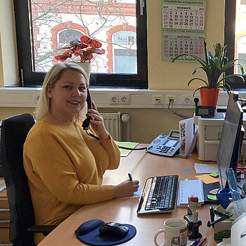 Eine freundliche Frau führt ein Beratungsgespräch am Telefon