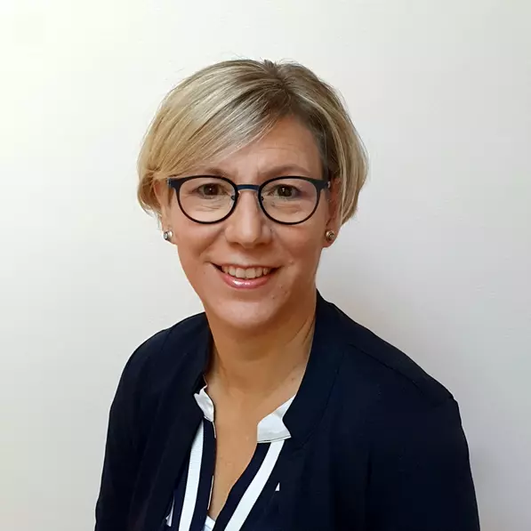 Eine Frau mit Brille im Portrait fotografiert lächelt.
