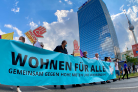 Demonstrationszug mit einem Transparent "Wohnen für alle" vor dem Berliner Fernsehturm