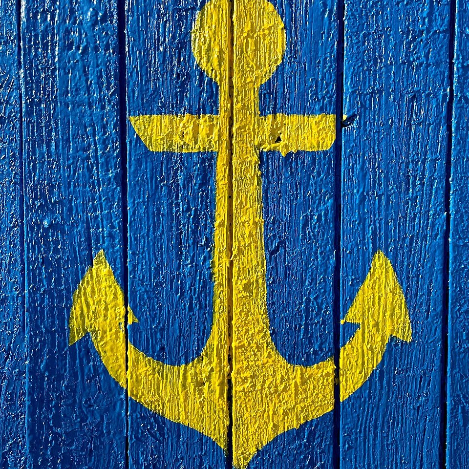 Ein gelber Anker gemalt auf eine blaue Holztür.
