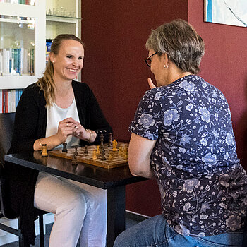 Zwei Menschen sitzen an einem Tisch und spielen Schach in der Begegnungsstätte Ambulantes Zentrum des KIELER FENSTER e.V.