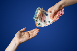 Hand überreicht anderer Hand einen Bündel Geldscheine