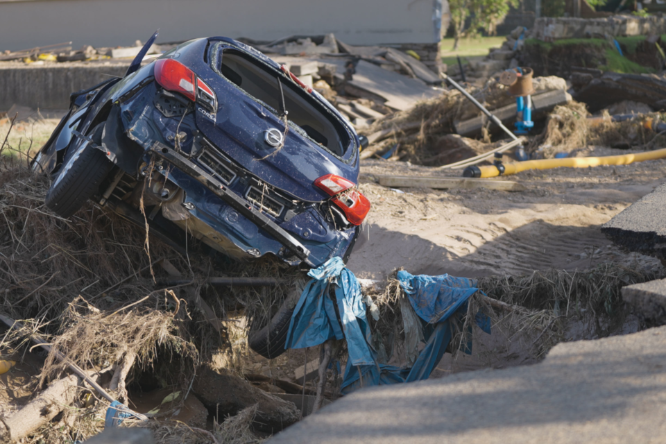 Trümmerlandschaft nach der Überschwemmung: Ein zerstörtes Auto liegt in einer aufgerissenen Straße.