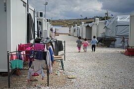 Drei Kinder laufen zwischen Unterkünften einer Flüchtlingsunterkunft.