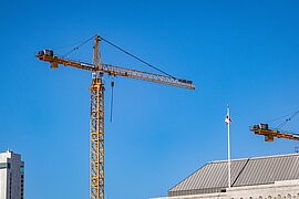Blauer Himmel, davor ein gelber Baukran