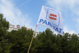 Eine Fahne mit dem Logo des Paritätischen, einem "Ist-Gleich"-Zeichen und Schrift: Parität.