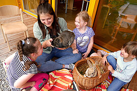 Junge Frau und drei Mädchen spielen mit Kaninchen