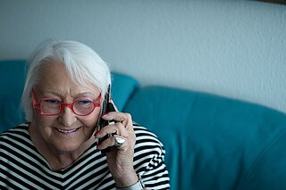 Porträt einer lachenden Frau am Telefon