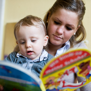Eine junge Mutter aus einer Wohngruppe liest ihrem Kind aus einem Bilderbuch vor.