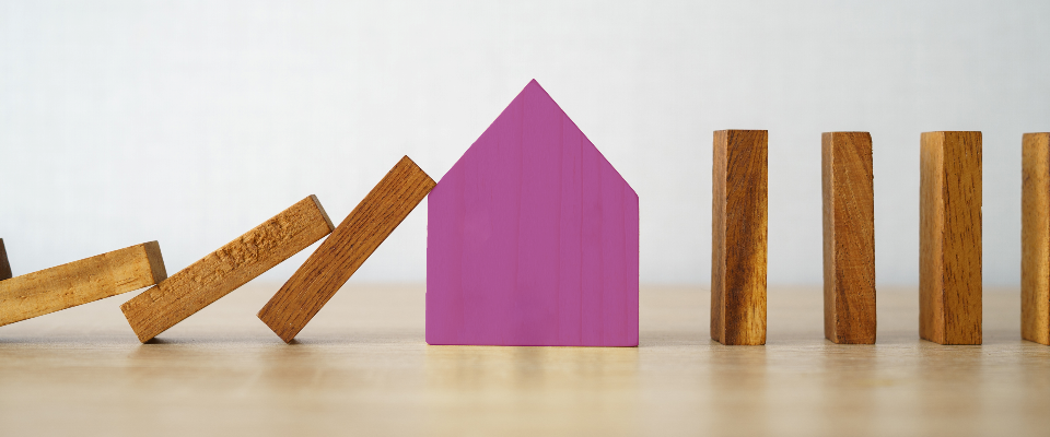 Fallende Dominosteine werden von einem violetten Haus angefangen. Die Steine rechts vom Haus bleiben sicher stehen.