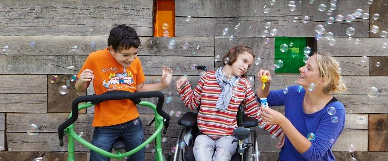 Zwei Kinder mit Behinderung freuen sich über Seifenblasen.