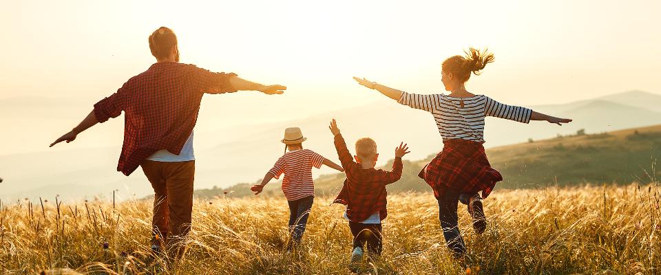 Familie mit 2 kindern rennen bei Sonnenuntergang durch Kornfeld