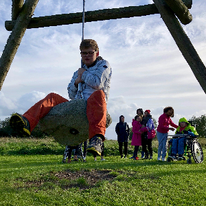 Ein Jugendlicher schaukelt auf einem hängenden Stein. Im Hintergrund beobachten ihn andere Jugendliche. © Tom Warnke