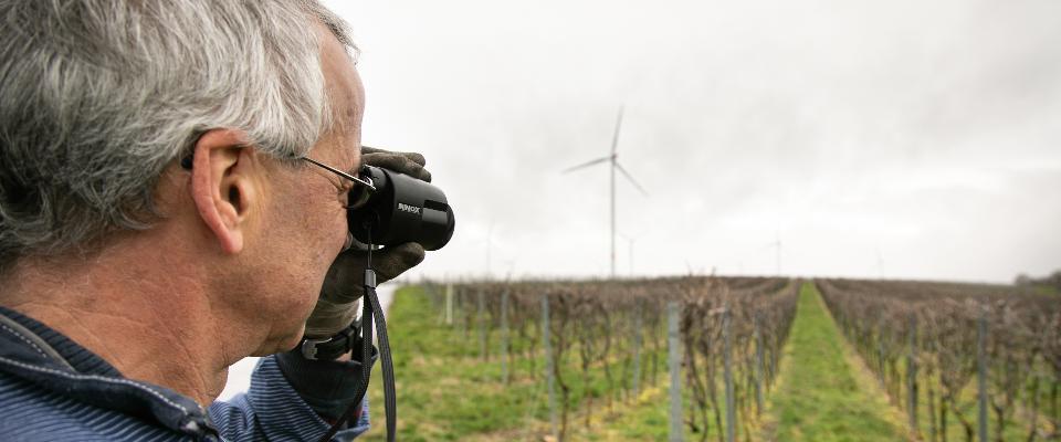 Ein Winzer blickt mit einem speziellen Fernrohr auf seinen Weinberg